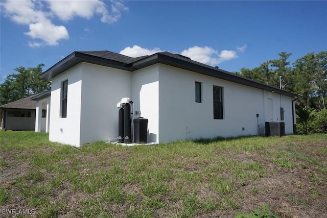 826 Alido Ave, Lehigh Acres, FL 33971 - view of side of property featuring stucco siding, central AC, and a lawn