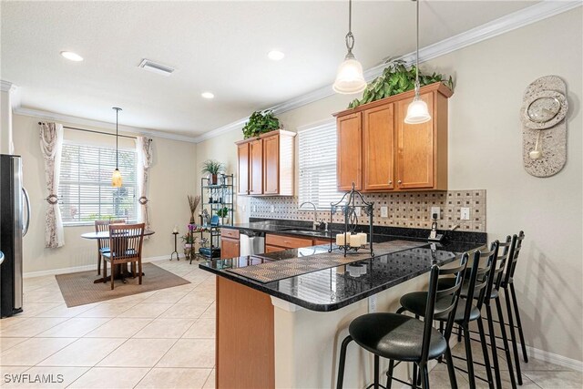 11430 Icarus Cir, Lehigh Acres, FL 33971 - kitchen featuring plenty of natural light, a peninsula, decorative backsplash, baseboards, and crown molding