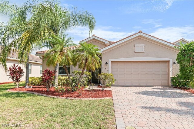 11430 Icarus Cir, Lehigh Acres, FL 33971 - view of front of property featuring stucco siding, decorative driveway, a front yard, and an attached garage