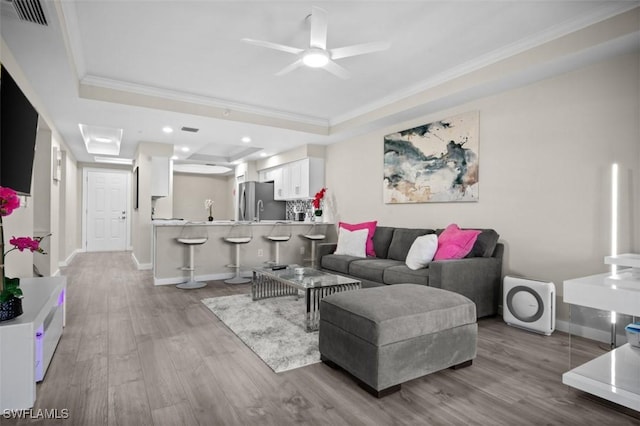 1793 Four Mile Cove Pkwy Unit 723, Cape Coral, FL 33990 - living room with a tray ceiling, ornamental molding, wood finished floors, a ceiling fan, and baseboards
