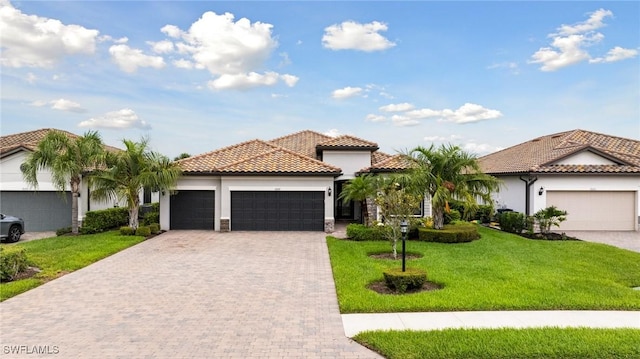 19197 Elston Way, Estero, FL 33928 - mediterranean / spanish house featuring a garage, a tile roof, decorative driveway, a front yard, and stucco siding