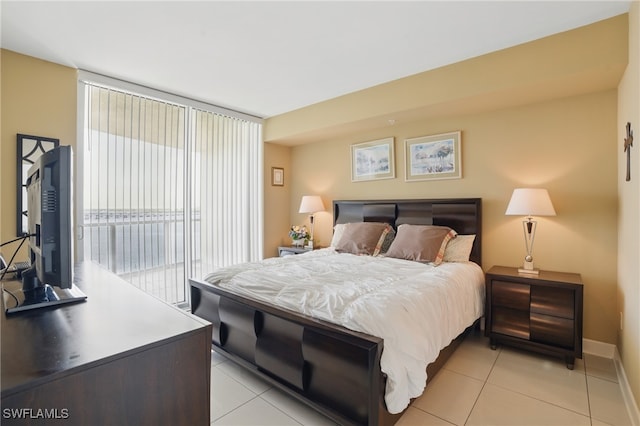 bedroom featuring access to exterior, light tile patterned floors, and baseboards