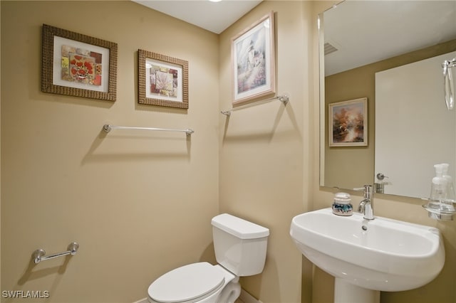 bathroom with a sink, toilet, and baseboards