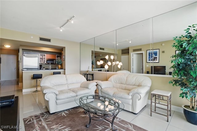 tiled living area featuring track lighting, baseboards, and a chandelier