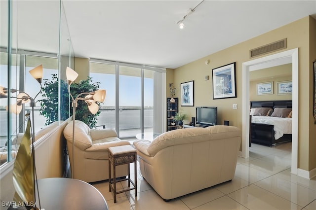 living area with light tile patterned floors, rail lighting, and a wall of windows