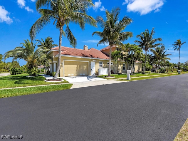 5667 Winkler Rd, Fort Myers, FL 33919 - view of front of house with stucco siding, an attached garage, driveway, a tiled roof, and a front yard