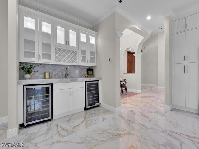 5667 Winkler Rd, Fort Myers, FL 33919 - indoor wet bar featuring beverage cooler, ornamental molding, light marble finish floors, arched walkways, and backsplash