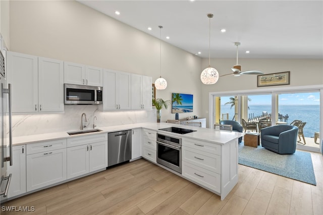 11410 Old Lodge Ln Unit 2C, Captiva, FL 33924 - kitchen featuring appliances with stainless steel finishes, high vaulted ceiling, a sink, a peninsula, and white cabinets