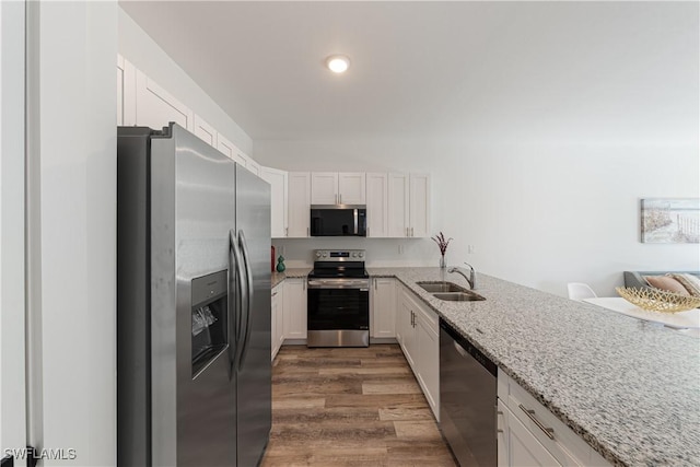 5205/5207 26th St SW, Lehigh Acres, FL 33973 - kitchen with appliances with stainless steel finishes, a sink, white cabinetry, wood finished floors, and light stone counters