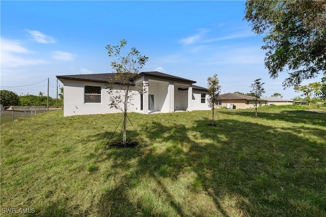 5205/5207 26th St SW, Lehigh Acres, FL 33973 - rear view of house with a lawn and stucco siding
