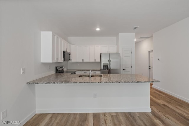 5205/5207 26th St SW, Lehigh Acres, FL 33973 - kitchen with stainless steel appliances, a peninsula, a sink, light stone counters, and white cabinetry
