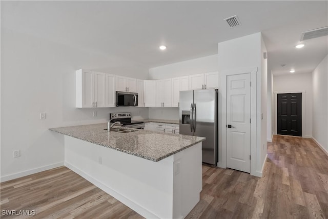 5205/5207 26th St SW, Lehigh Acres, FL 33973 - kitchen with stainless steel appliances, a peninsula, white cabinets, light wood-style floors, and recessed lighting