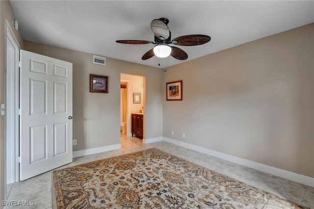 7065 Dennis Cir Unit F204, Naples, FL 34104 - unfurnished bedroom featuring light tile patterned floors, baseboards, ensuite bathroom, and a ceiling fan