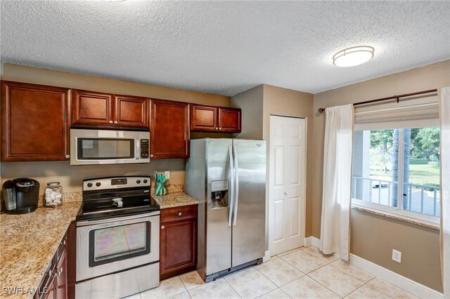 7065 Dennis Cir Unit F204, Naples, FL 34104 - kitchen with stainless steel appliances, a textured ceiling, light tile patterned floors, baseboards, and light stone countertops