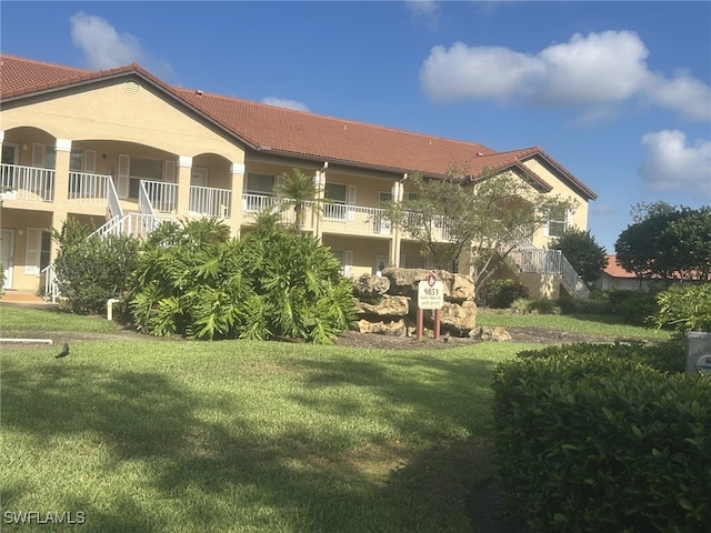 9851 Costa Mesa Ln Unit 308, Bonita Springs, FL 34135 - back of property featuring a tile roof, stairway, and a yard