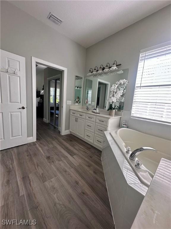 5489 Whispering Willow Way, Fort Myers, FL 33908 - full bath featuring double vanity, a garden tub, wood finished floors, and baseboards