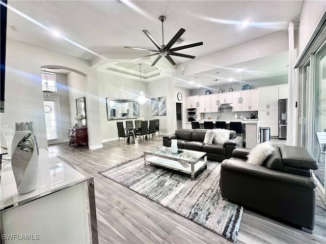 5489 Whispering Willow Way, Fort Myers, FL 33908 - living area featuring arched walkways, a ceiling fan, light wood-type flooring, baseboards, and a high ceiling