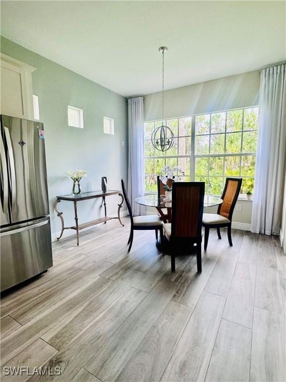 5489 Whispering Willow Way, Fort Myers, FL 33908 - dining space with a chandelier, light wood finished floors, and baseboards