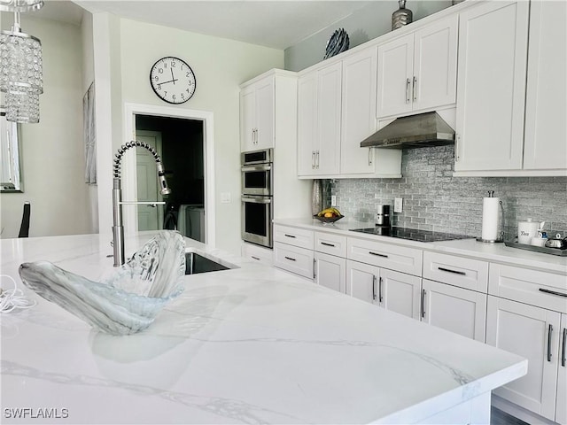 5489 Whispering Willow Way, Fort Myers, FL 33908 - kitchen featuring under cabinet range hood, black electric stovetop, stainless steel double oven, backsplash, and white cabinetry