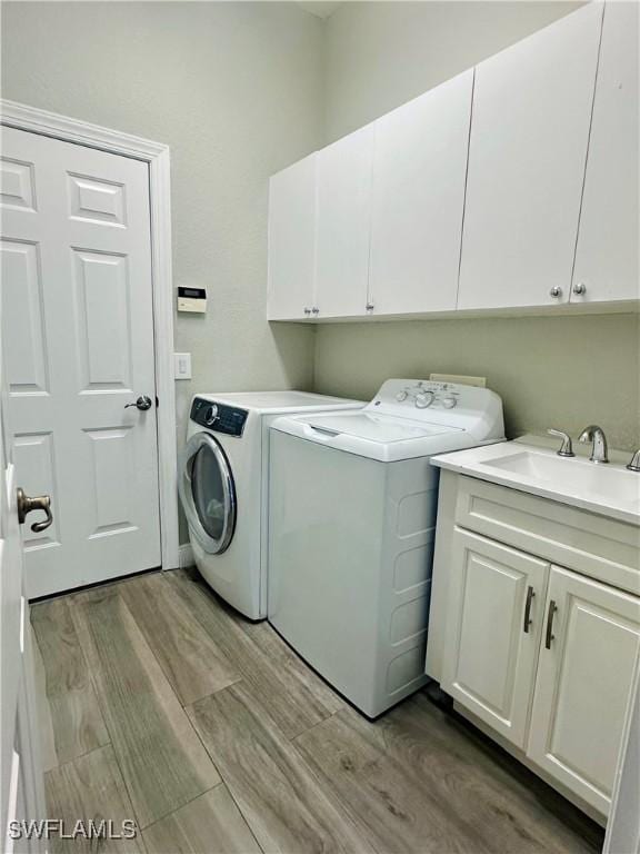 5489 Whispering Willow Way, Fort Myers, FL 33908 - washroom featuring washing machine and clothes dryer, cabinet space, and light wood-style floors