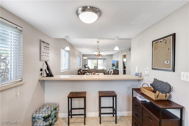 2100 Barkeley Ln Unit 1, Fort Myers, FL 33907 - kitchen featuring a kitchen breakfast bar, hanging light fixtures, baseboards, dark brown cabinets, and light countertops