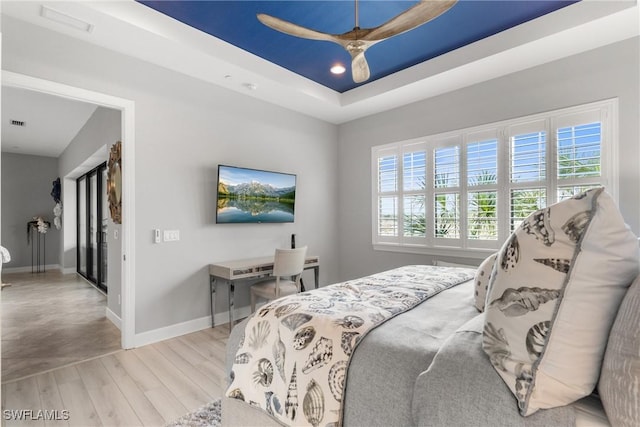 8761 Bellano Ct Unit 202, Naples, FL 34119 - bedroom featuring wood finished floors, baseboards, a raised ceiling, and a ceiling fan