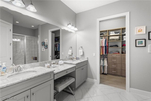 8761 Bellano Ct Unit 202, Naples, FL 34119 - bathroom with double vanity, a walk in closet, a stall shower, and baseboards