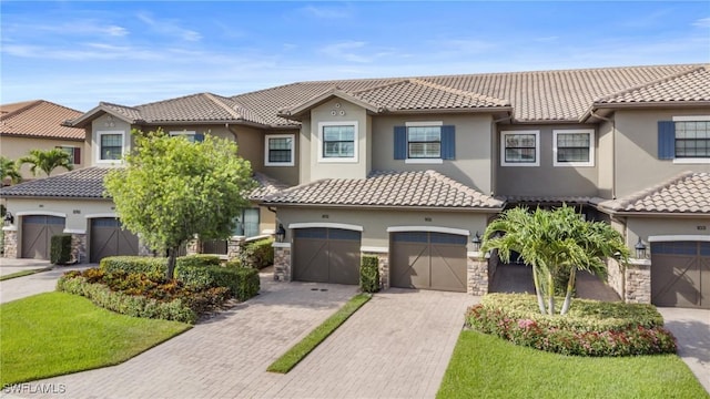 8761 Bellano Ct Unit 202, Naples, FL 34119 - view of front facade featuring stucco siding, a tile roof, driveway, and stone siding