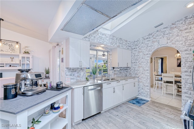 25379 Paladin Ln, Punta Gorda, FL 33983 - kitchen with dishwasher, arched walkways, white cabinetry, light wood-type flooring, and a sink