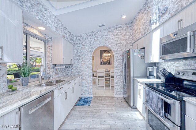 25379 Paladin Ln, Punta Gorda, FL 33983 - kitchen featuring stainless steel appliances, a sink, arched walkways, and white cabinetry