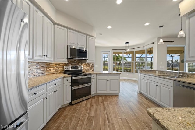 1069 SW 57th St, Cape Coral, FL 33914 - kitchen featuring appliances with stainless steel finishes, light wood-style floors, recessed lighting, white cabinets, and tasteful backsplash