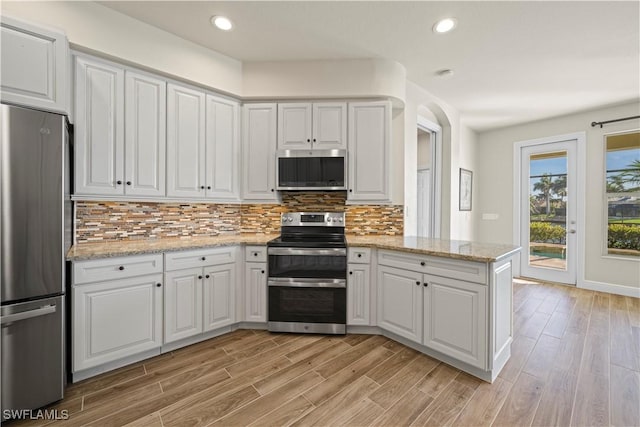 1069 SW 57th St, Cape Coral, FL 33914 - kitchen with appliances with stainless steel finishes, light wood-style flooring, tasteful backsplash, white cabinetry, and recessed lighting