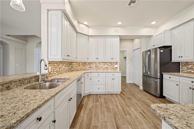 1069 SW 57th St, Cape Coral, FL 33914 - kitchen featuring stainless steel appliances, white cabinets, light wood finished floors, backsplash, and light stone counters