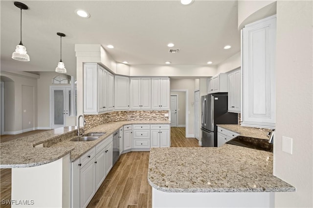 1069 SW 57th St, Cape Coral, FL 33914 - kitchen featuring a peninsula, stainless steel appliances, light wood finished floors, backsplash, and light stone counters