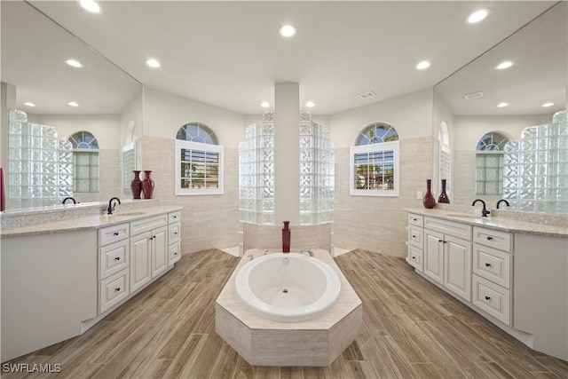 1069 SW 57th St, Cape Coral, FL 33914 - bathroom featuring tile walls, two vanities, a bath, recessed lighting, and wood finished floors