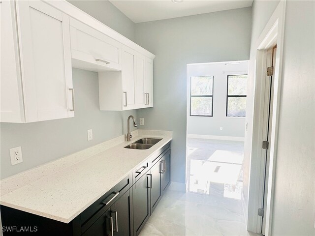 3016 6th St W, Lehigh Acres, FL 33971 - kitchen with a sink, white cabinetry, light stone countertops, and baseboards