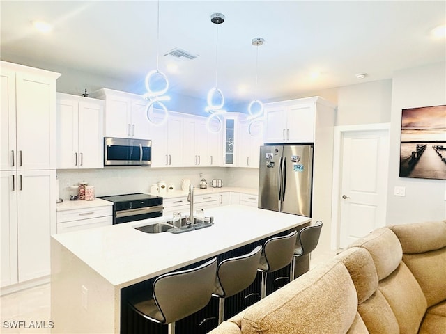 3016 6th St W, Lehigh Acres, FL 33971 - kitchen featuring appliances with stainless steel finishes, a sink, a breakfast bar, a center island with sink, and white cabinetry