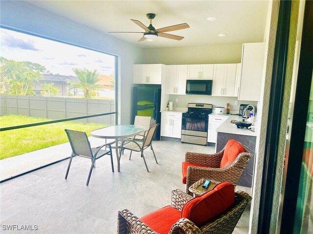 3016 6th St W, Lehigh Acres, FL 33971 - kitchen featuring gas range, black microwave, a sink, white cabinetry, and a ceiling fan