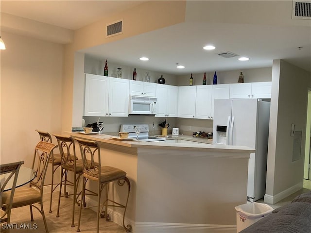 1516 SW 50th St Unit 104, Cape Coral, FL 33914 - kitchen with white appliances, white cabinetry, a peninsula, a kitchen bar, and recessed lighting