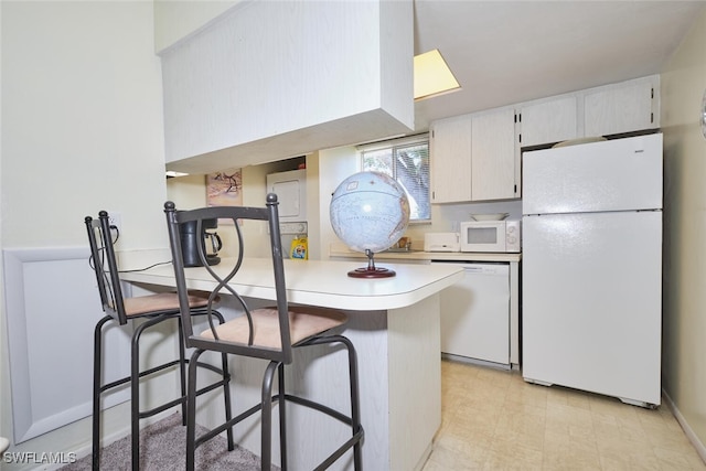 3350 Alouette Cir Unit 1, Fort Myers, FL 33907 - kitchen featuring white appliances, light countertops, a peninsula, a breakfast bar area, and white cabinets