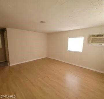 spare room with a wall mounted air conditioner, wood finished floors, and baseboards