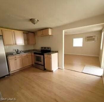kitchen with stainless steel appliances, light wood-type flooring, a sink, an AC wall unit, and baseboards