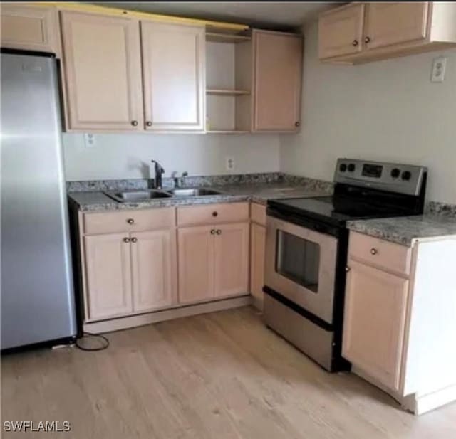 kitchen with stainless steel appliances, light wood-style flooring, open shelves, a sink, and light stone counters