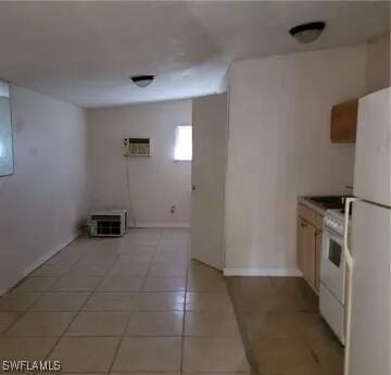 kitchen featuring white appliances, a wall mounted air conditioner, light tile patterned floors, and baseboards