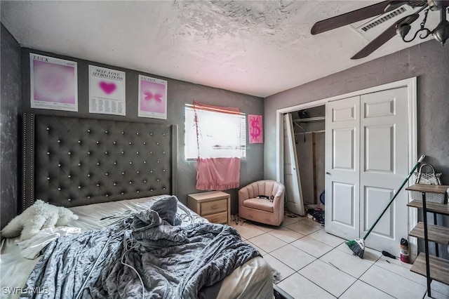 bedroom featuring tile patterned floors, a closet, ceiling fan, and a textured ceiling