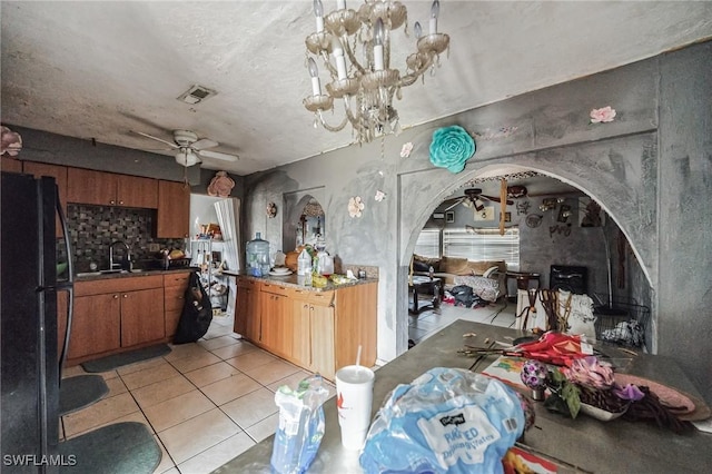 kitchen with freestanding refrigerator, ceiling fan, brown cabinets, light tile patterned floors, and a textured ceiling