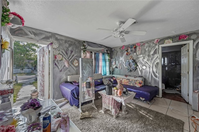 living area featuring ceiling fan, a textured ceiling, and tile patterned flooring