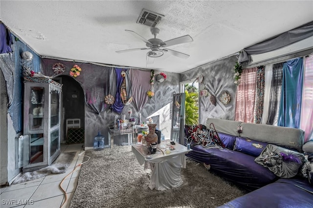 living room featuring a textured ceiling, ceiling fan, and tile patterned floors