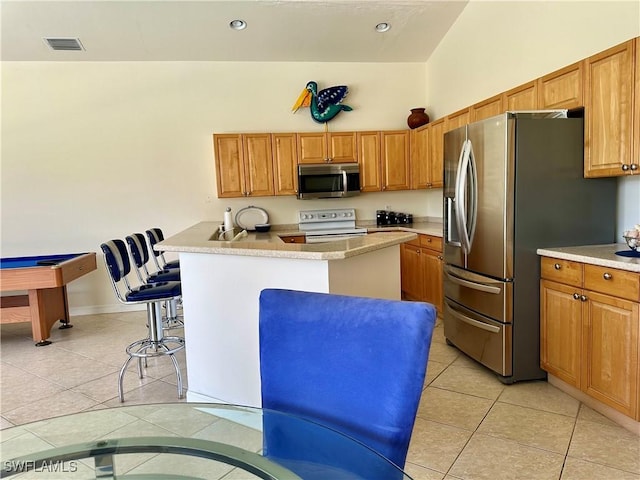 28171 L Burton Fletcher Ct, Bonita Springs, FL 34135 - kitchen with stainless steel appliances, light tile patterned floors, a breakfast bar area, light countertops, and brown cabinets