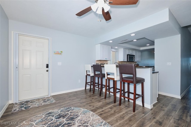 1124 SW 48th Ter Unit 208, Cape Coral, FL 33914 - kitchen featuring stainless steel microwave, dark wood-style floors, a ceiling fan, a kitchen breakfast bar, and baseboards
